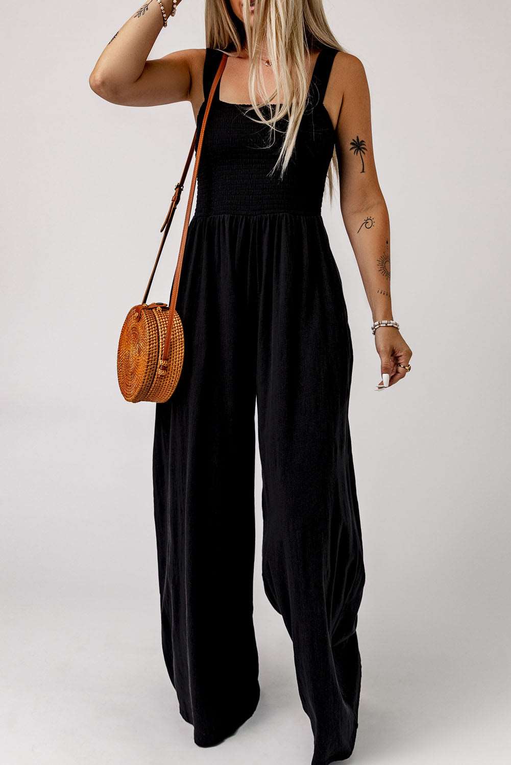 A woman wearing the Lots To Love Wide Leg Romper with a round purse, showcasing springtime fashion and elegance.