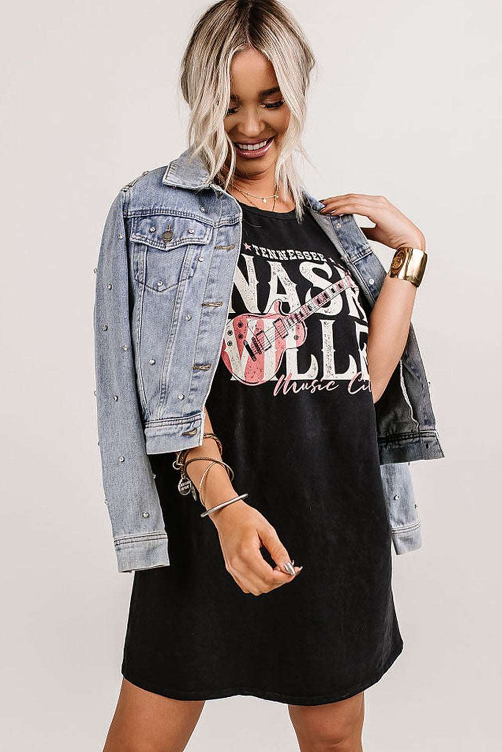 A woman wearing a denim jacket and a black dress, showcasing the Nashville Music Festival T-Shirt Dress.